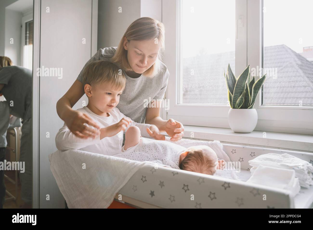 Femme et garçon qui s'occupe de bébé dormant sur une table à langer à la maison Banque D'Images