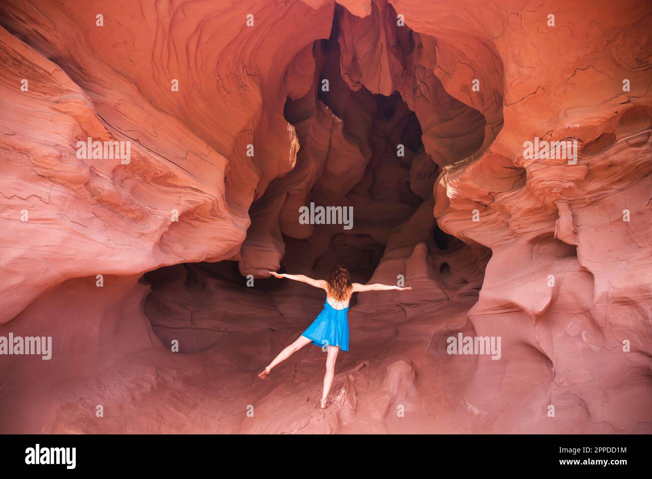 Jeune femme debout sur une jambe avec les bras étirés dans la grotte Banque D'Images