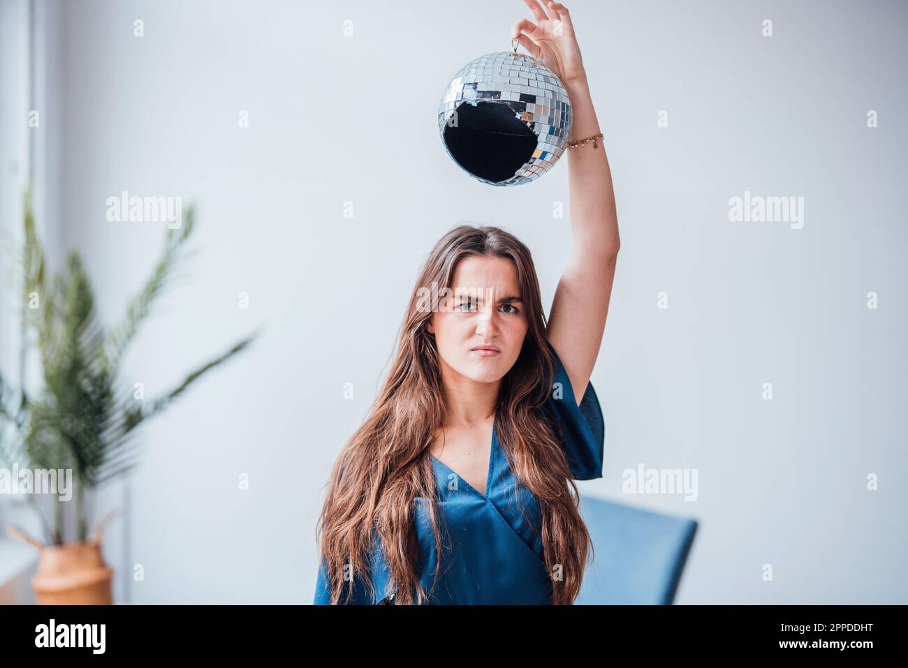 Femme d'affaires en colère tenant une balle disco cassée sur la tête Banque D'Images