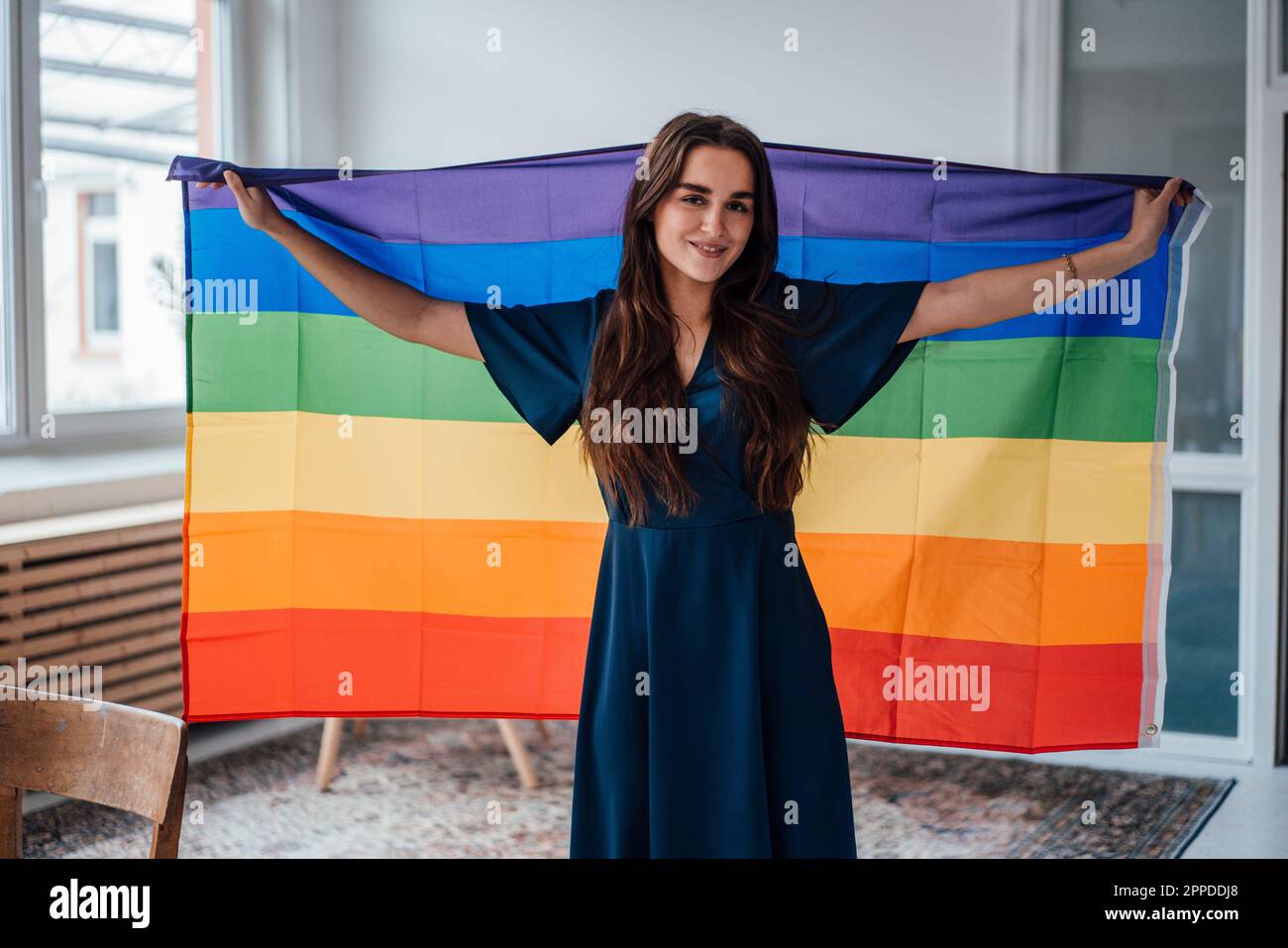 Femme d'affaires souriante avec drapeau arc-en-ciel debout au bureau Banque D'Images