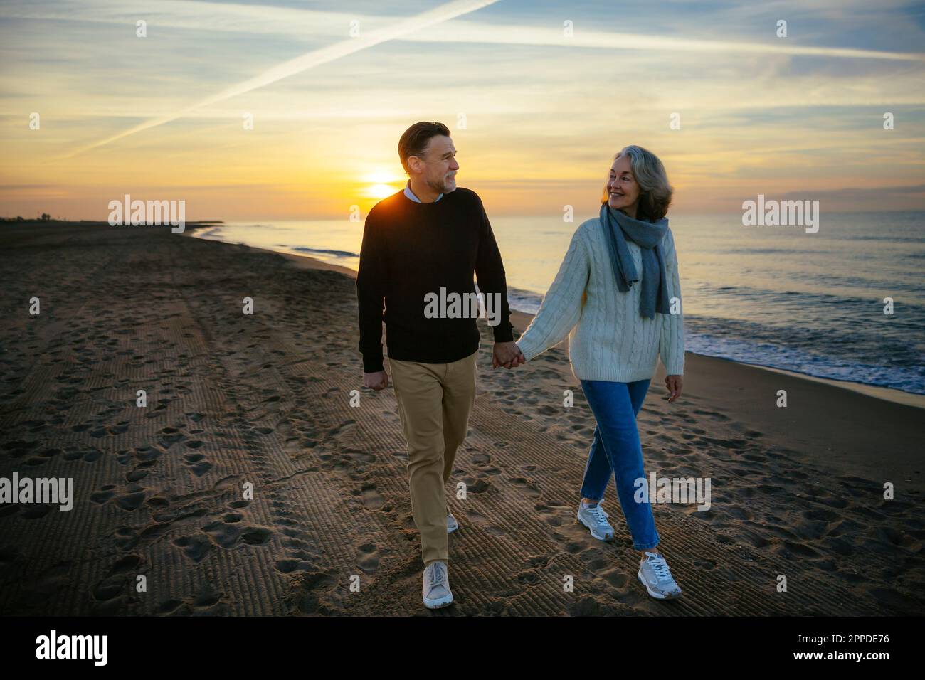 Couple mûr souriant marchant à la plage Banque D'Images