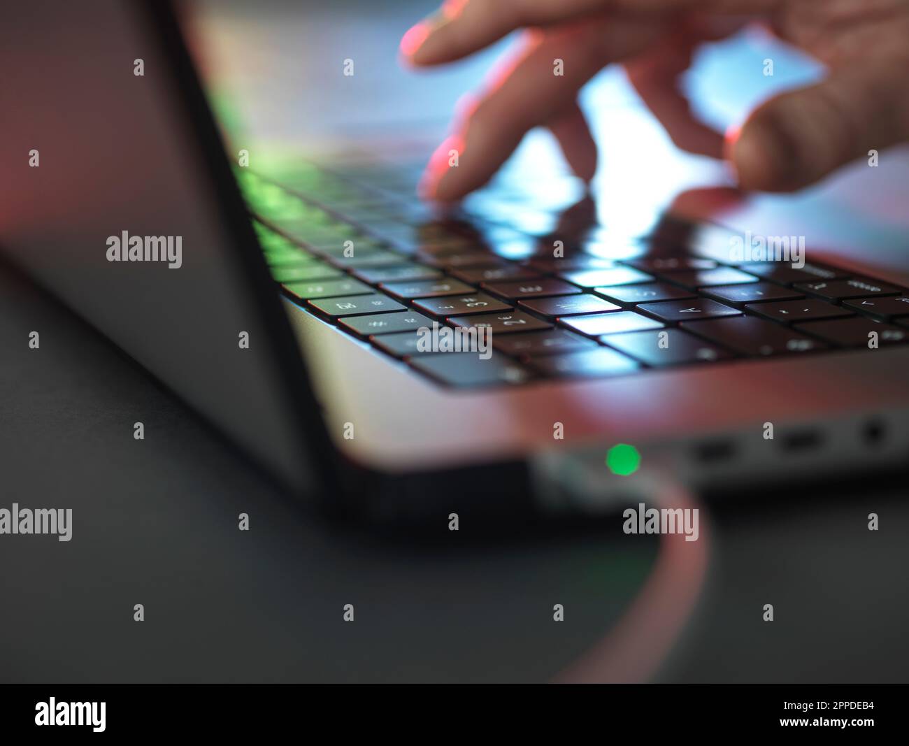Saisie manuelle sur clavier lumineux pour ordinateur portable dans l'obscurité au bureau à domicile Banque D'Images