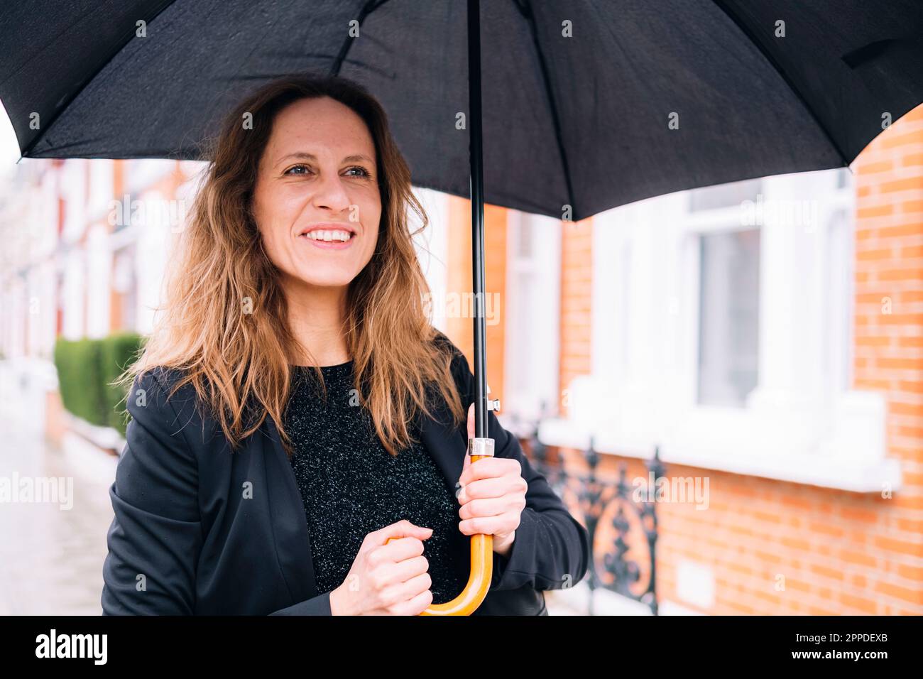 Bonne femme tenant un parapluie noir Banque D'Images