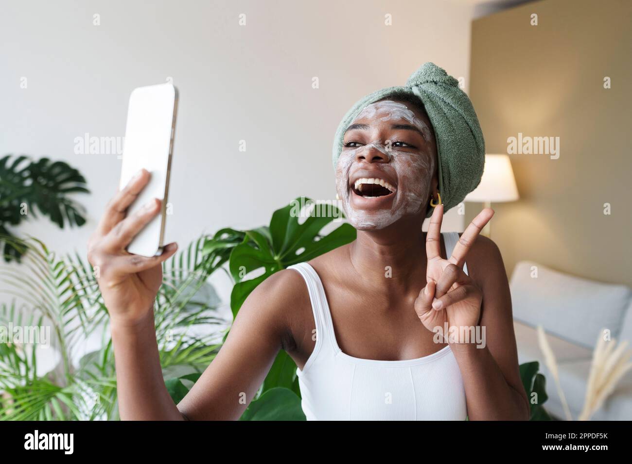 Femme joyeuse montrant le geste du signe de paix et prenant le selfie à travers le smartphone Banque D'Images