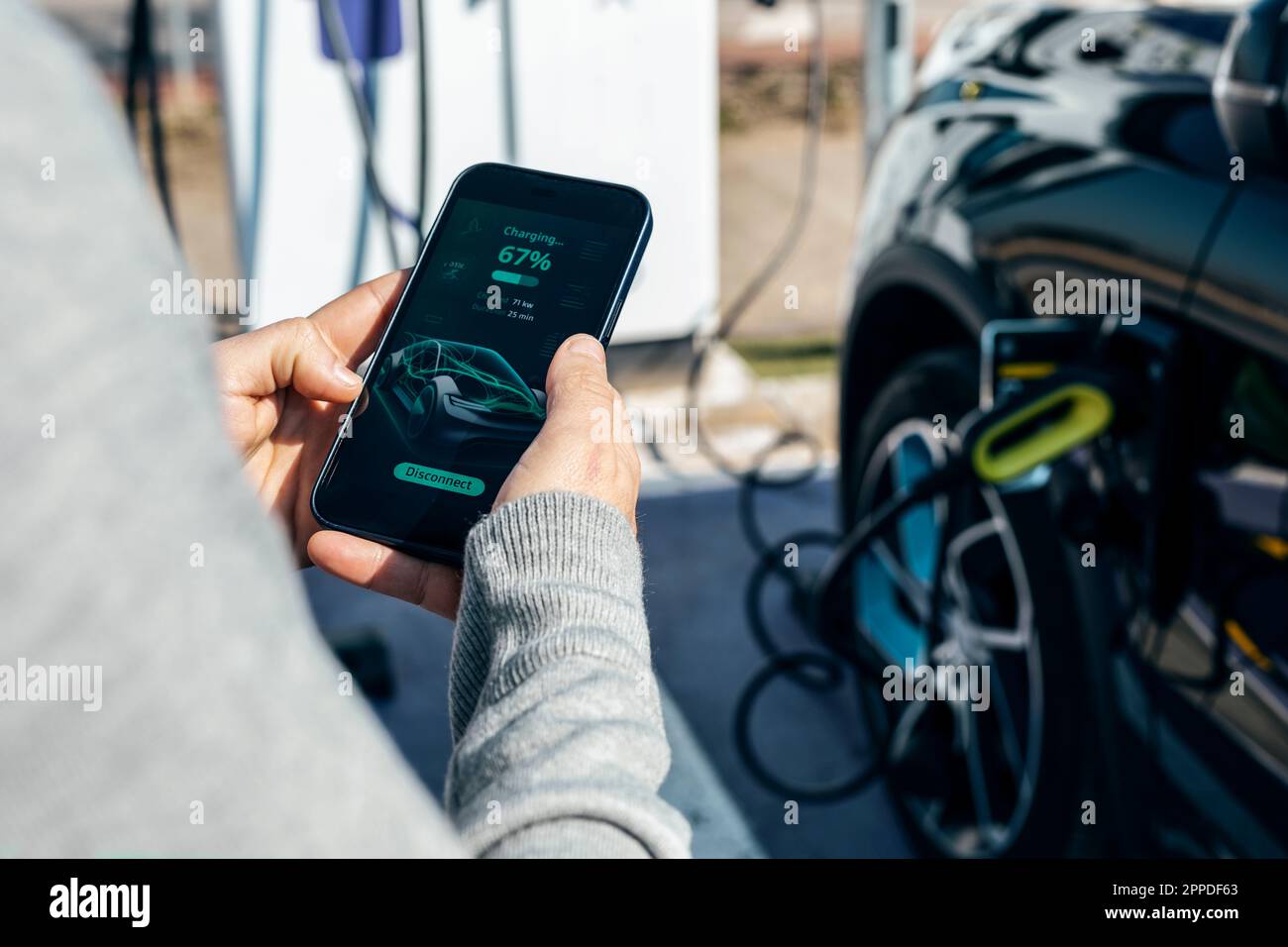 Homme vérifiant l'état de charge de la voiture sur le smartphone Banque D'Images