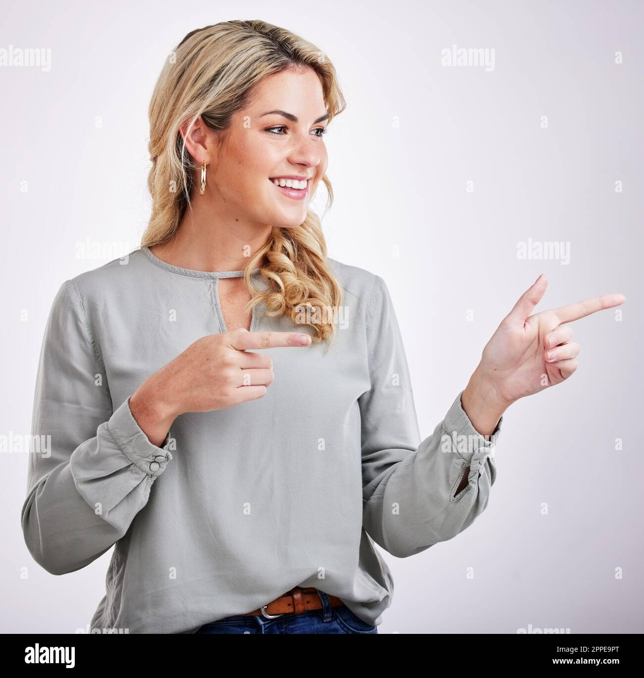 Heureux, femme et pointant à la publicité sur fond blanc de l'offre, l'information et la marque bientôt à venir. Jeune femme, geste et Banque D'Images