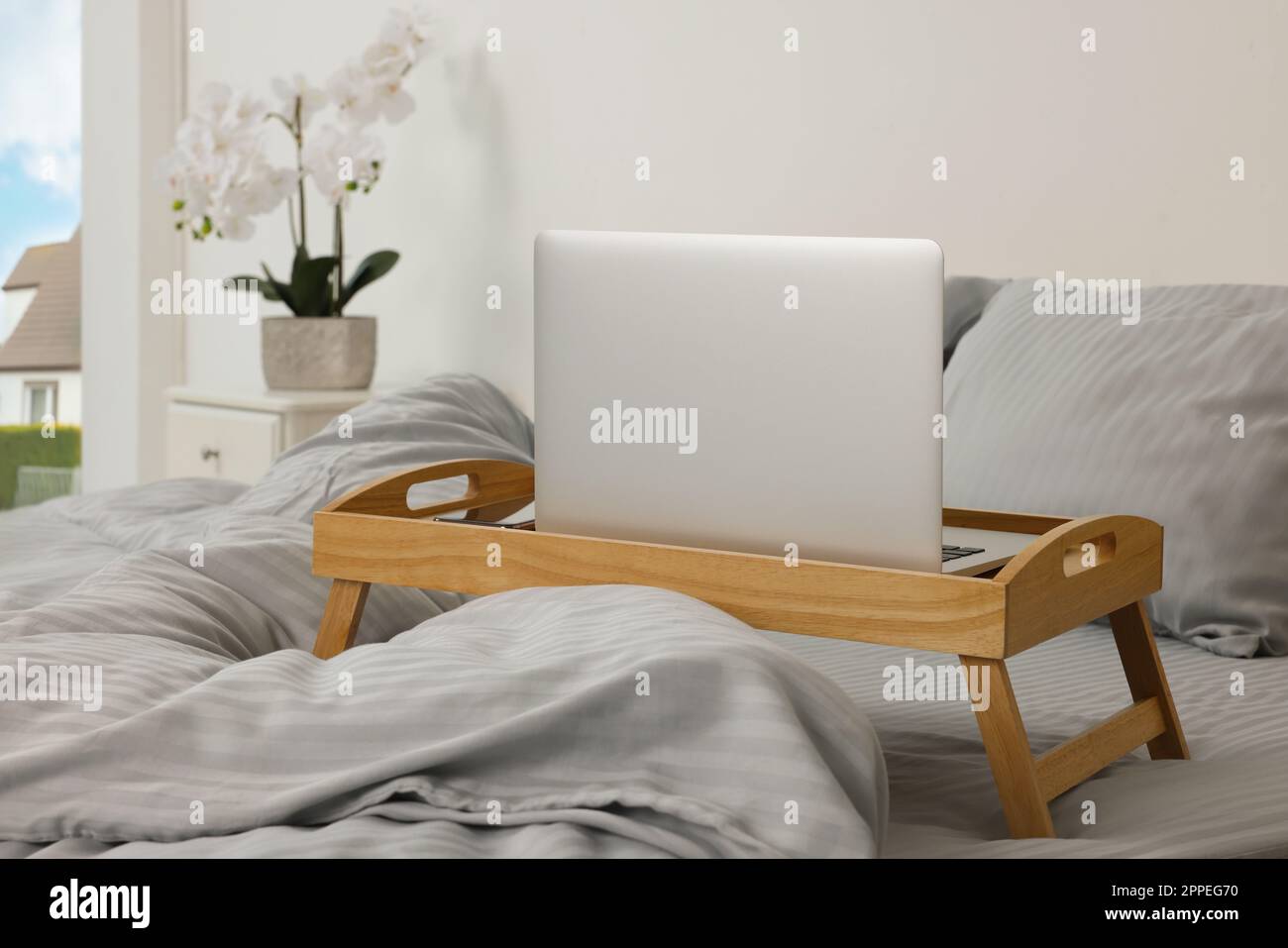 Plateau table en bois avec ordinateur portable et smartphone sur le lit à l'intérieur Banque D'Images