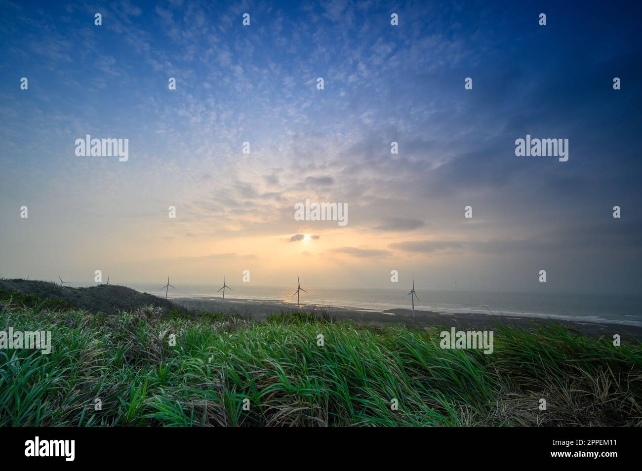 Le moulin à vent tourne pour produire de l'électricité, le beau coucher de soleil au bord de la mer. Houlong le Cap, une célèbre attraction touristique. Comté de Miaoli, Taïwan Banque D'Images