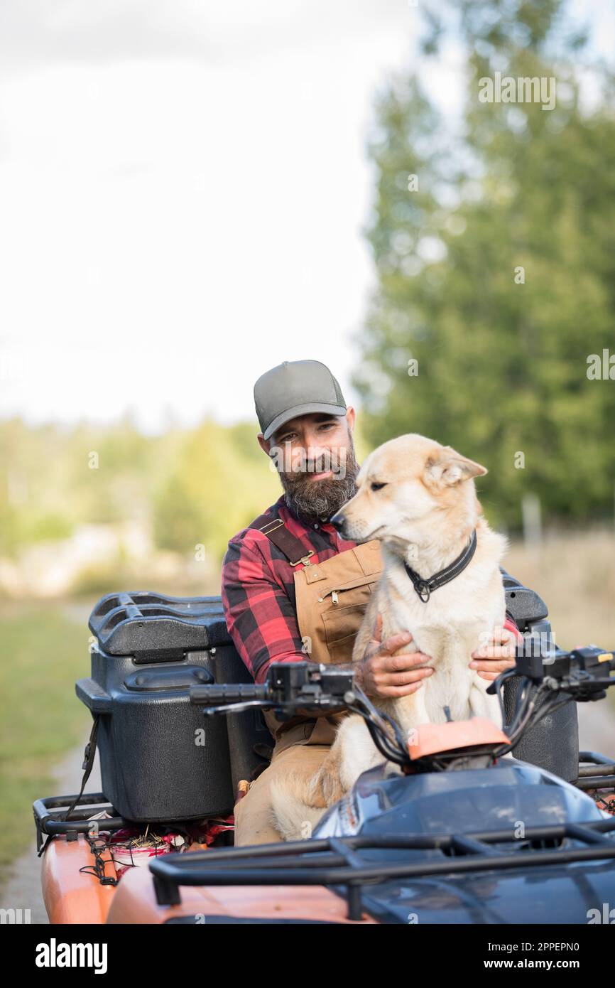 Agriculteur de sexe masculin avec chien à quatre roues Banque D'Images