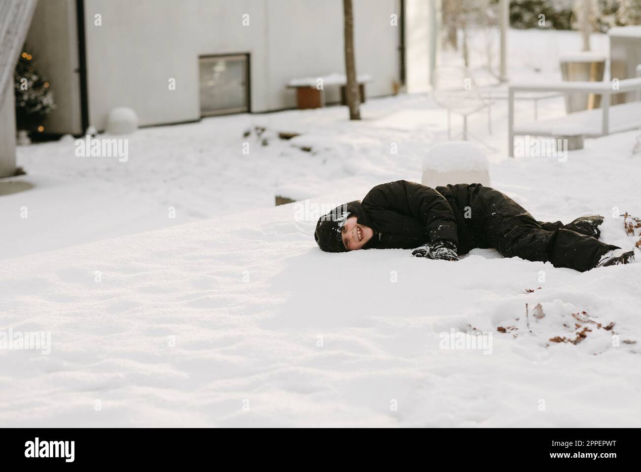 Garçon souriant couché sur la neige en hiver Banque D'Images