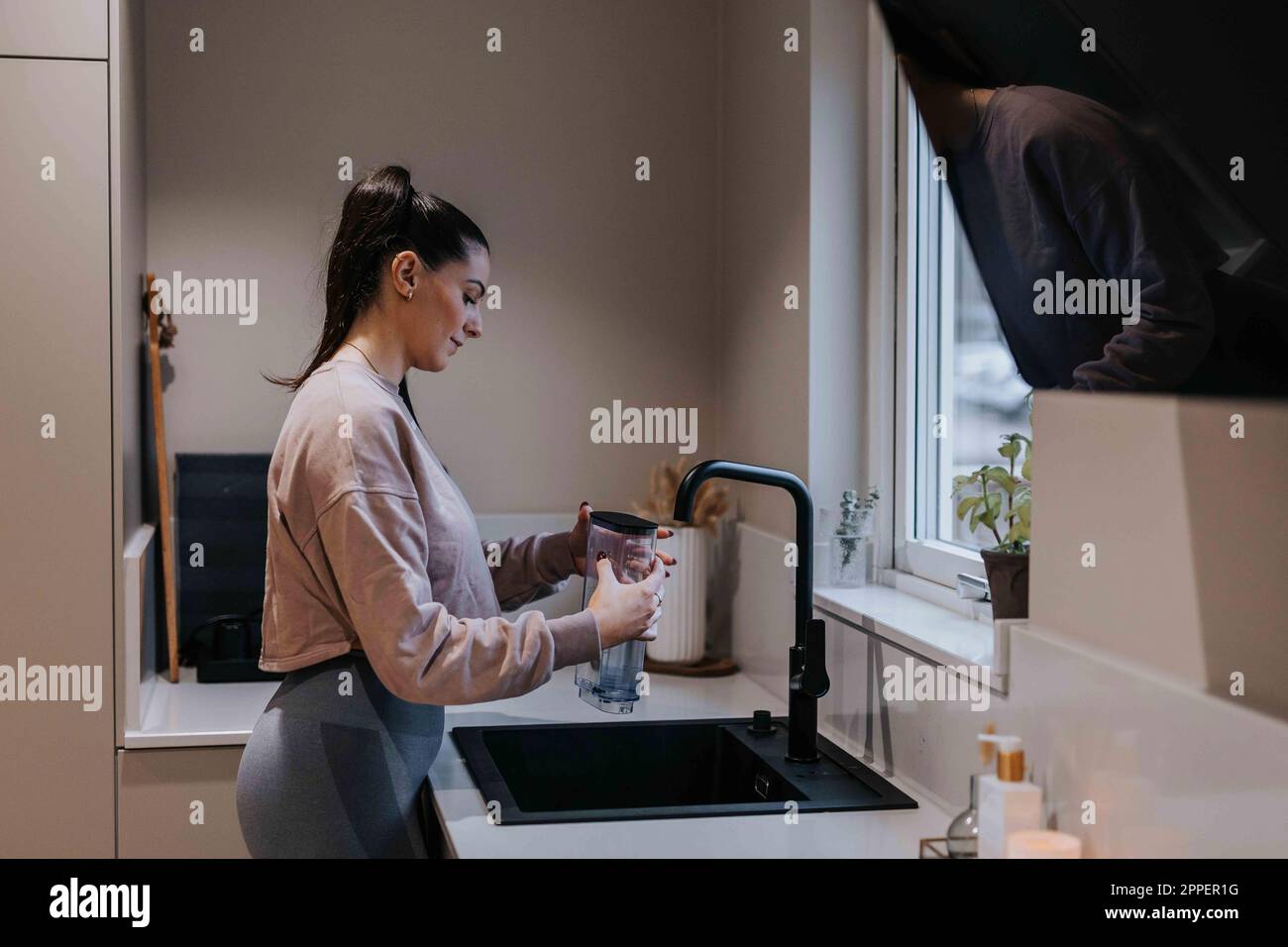 Femme en cuisine remplissant la carafe avec de l'eau Banque D'Images