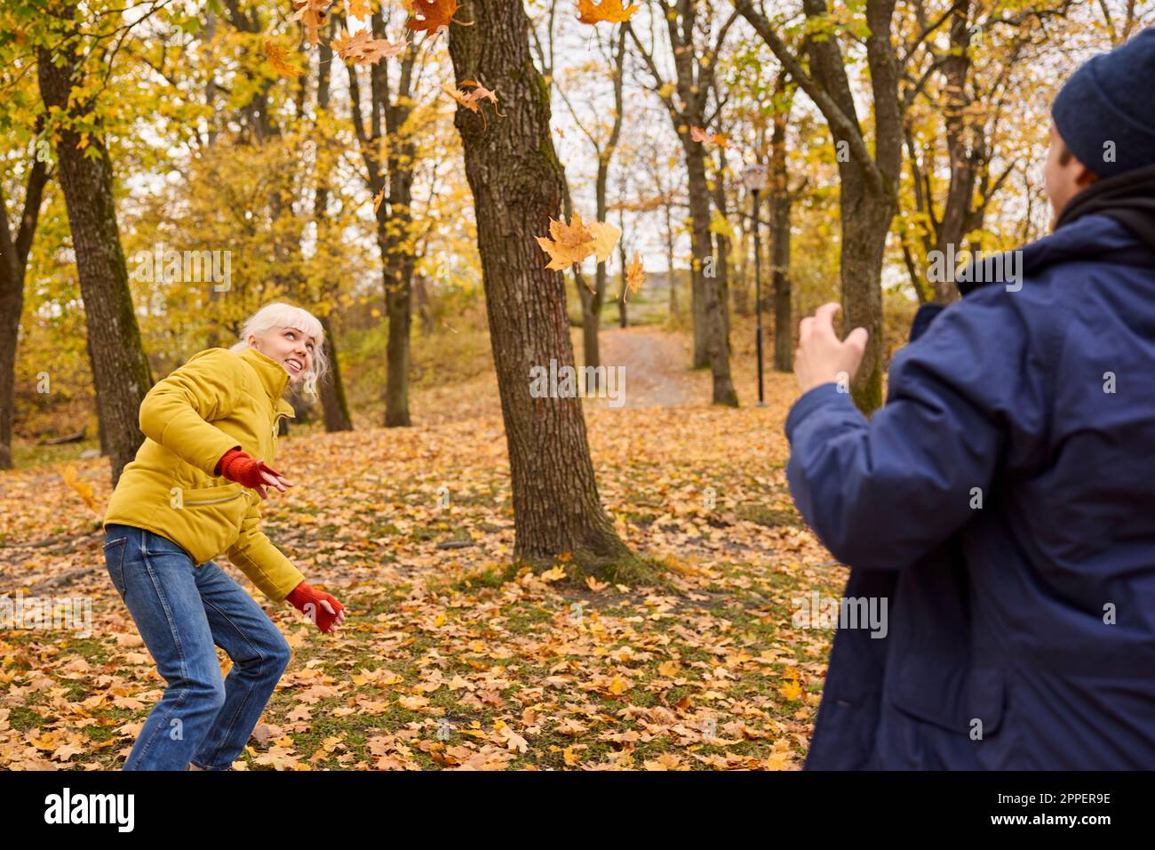 De jeunes amis heureux jetant des feuilles d'automne Banque D'Images