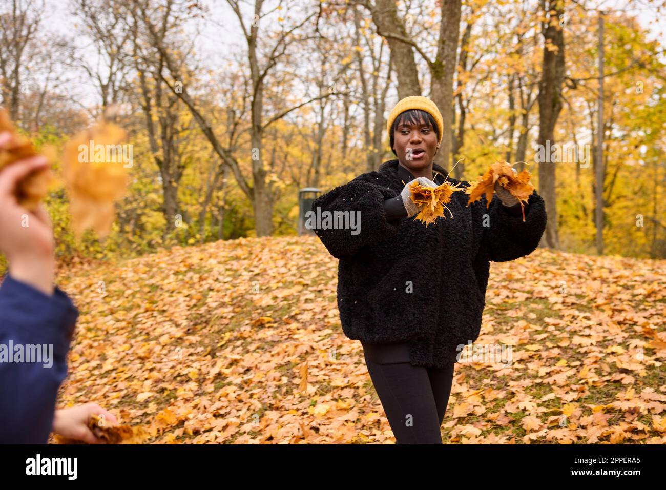 Femme souriante jetant des feuilles d'automne Banque D'Images