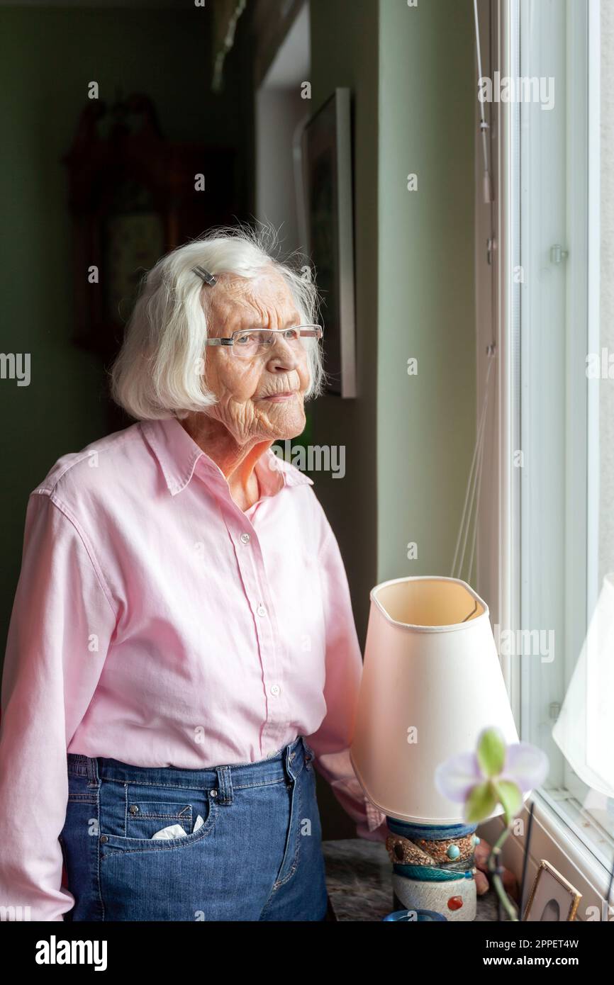 Senior woman looking through window Banque D'Images