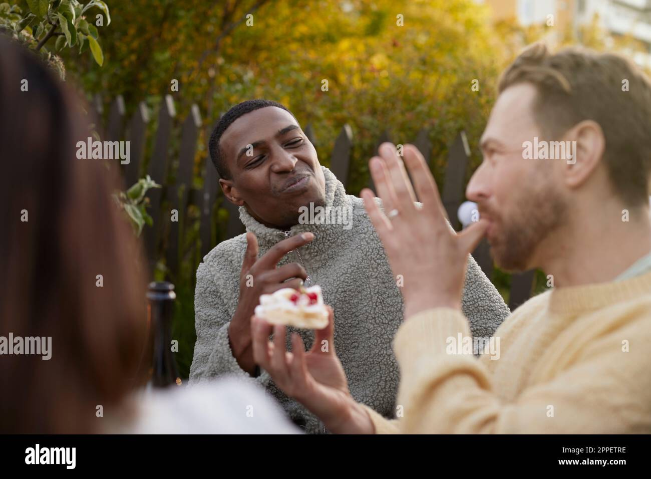 Souriants hommes mangeant du gâteau dans le jardin Banque D'Images