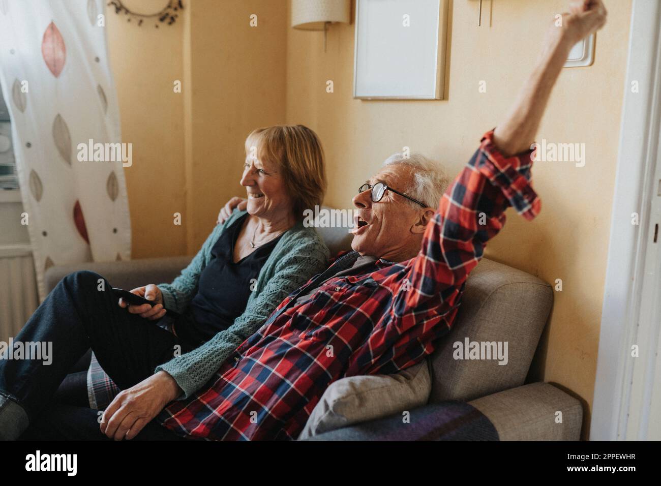 Couple senior assis sur un canapé et chantant Banque D'Images