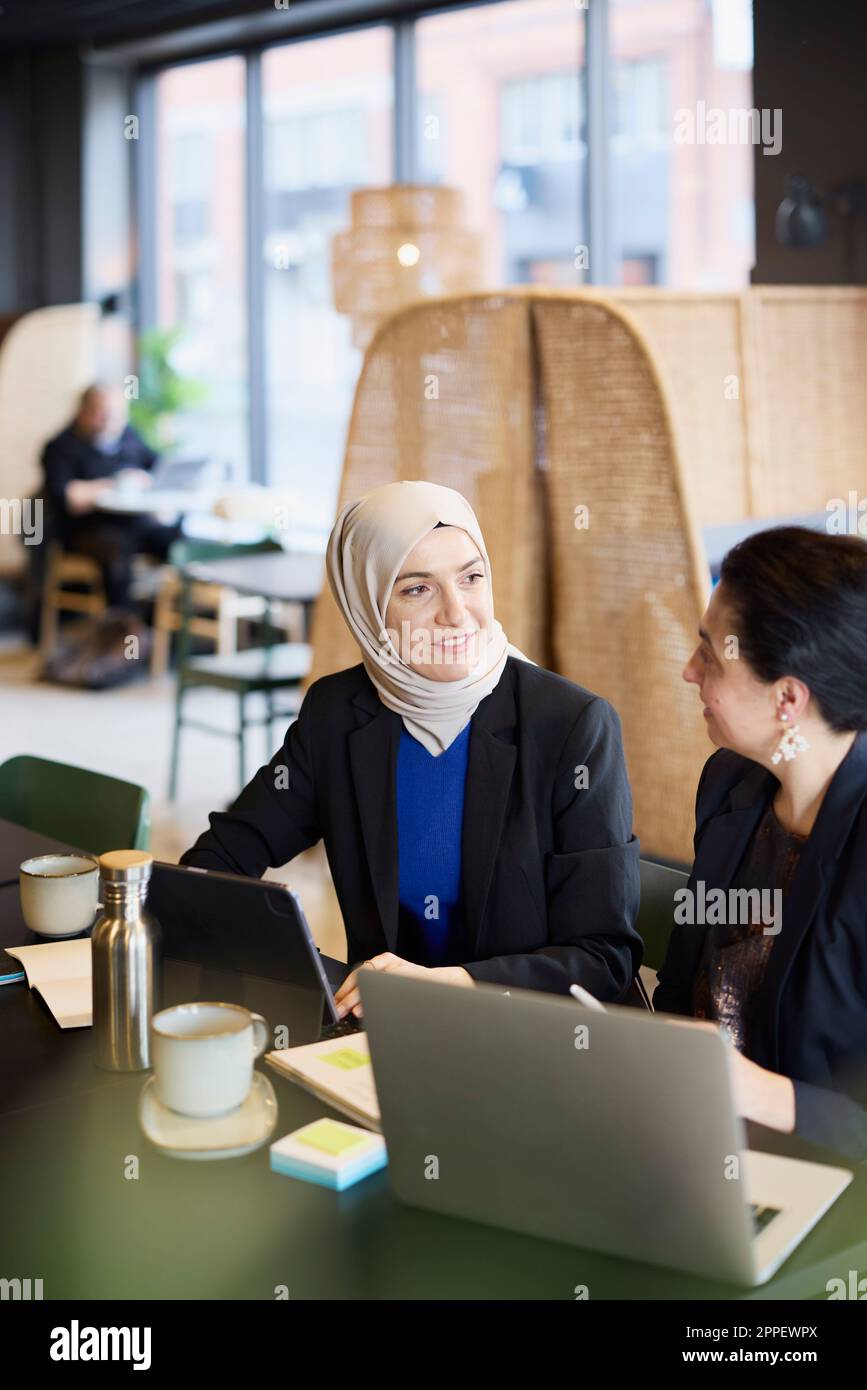 Businesswomen using digital tablet in cafe Banque D'Images