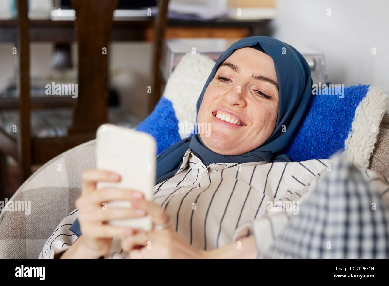 Femme sur canapé avec téléphone portable Banque D'Images