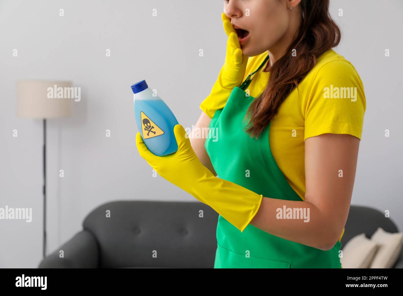 Femme regardant une bouteille de produit chimique toxique domestique avec un panneau d'avertissement, gros plan Banque D'Images