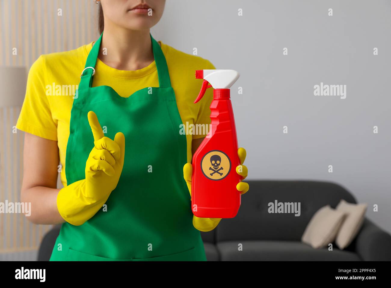 Femme montrant une bouteille de produit chimique toxique domestique avec un panneau d'avertissement, gros plan Banque D'Images