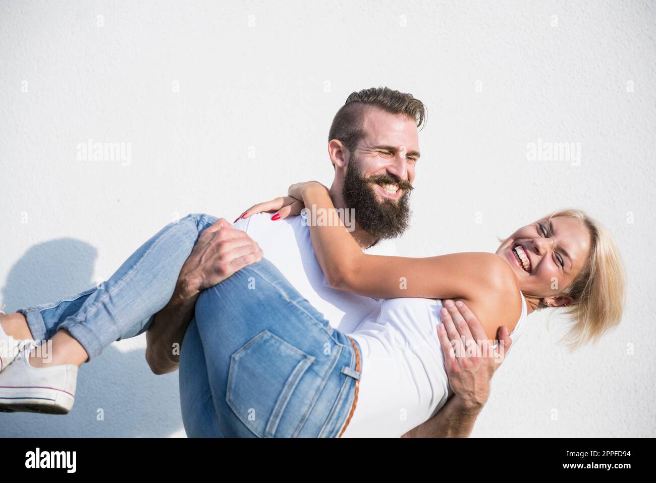 Jeune homme heureux portant une femme devant le mur, Bavière, Allemagne Banque D'Images