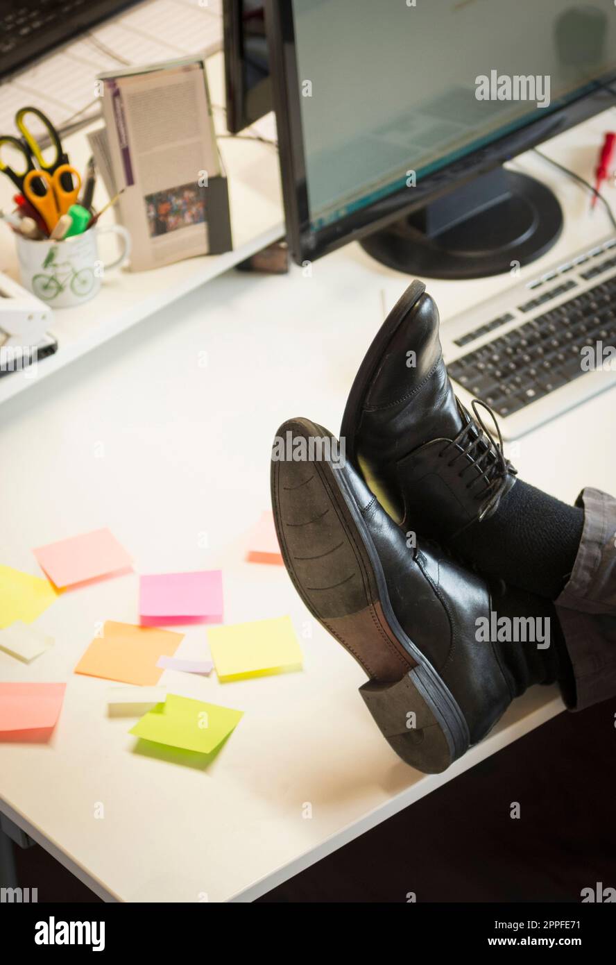 Bas section d'un homme d'affaires pieds sur le bureau dans un bureau, Bavière, Allemagne Banque D'Images