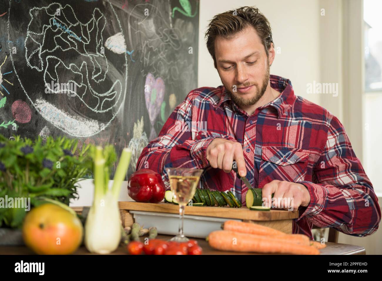 Homme en train de trancher des légumes sur une planche à découper, Munich, Bavière, Allemagne Banque D'Images