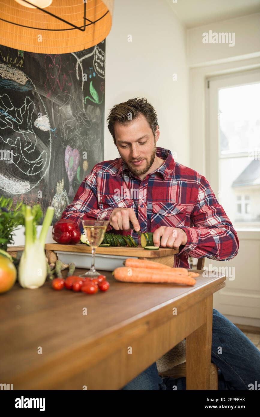 Homme en train de trancher des légumes sur une planche à découper, Munich, Bavière, Allemagne Banque D'Images