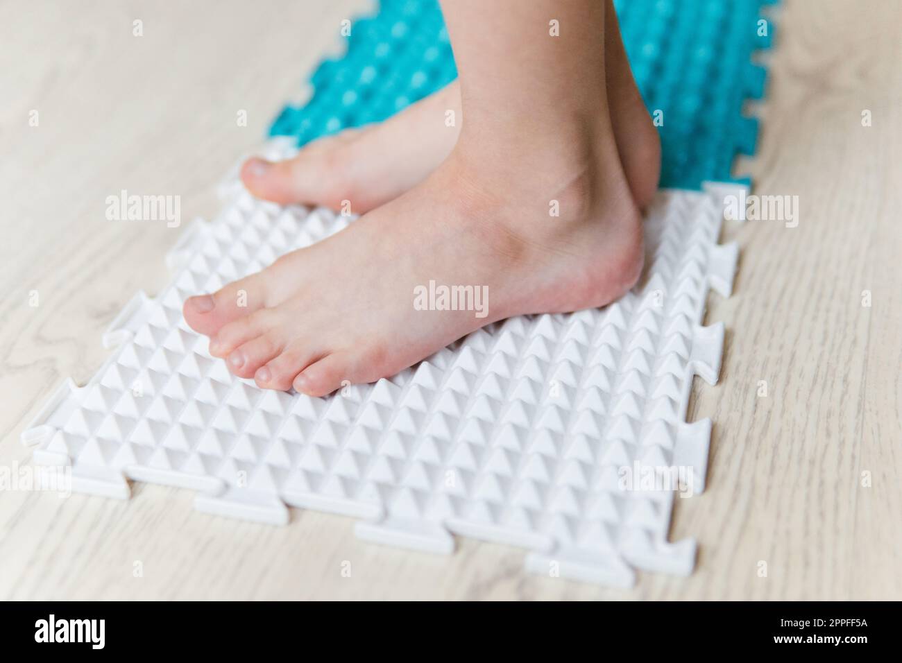 les pieds de l'enfant sur un tapis orthopédique Banque D'Images
