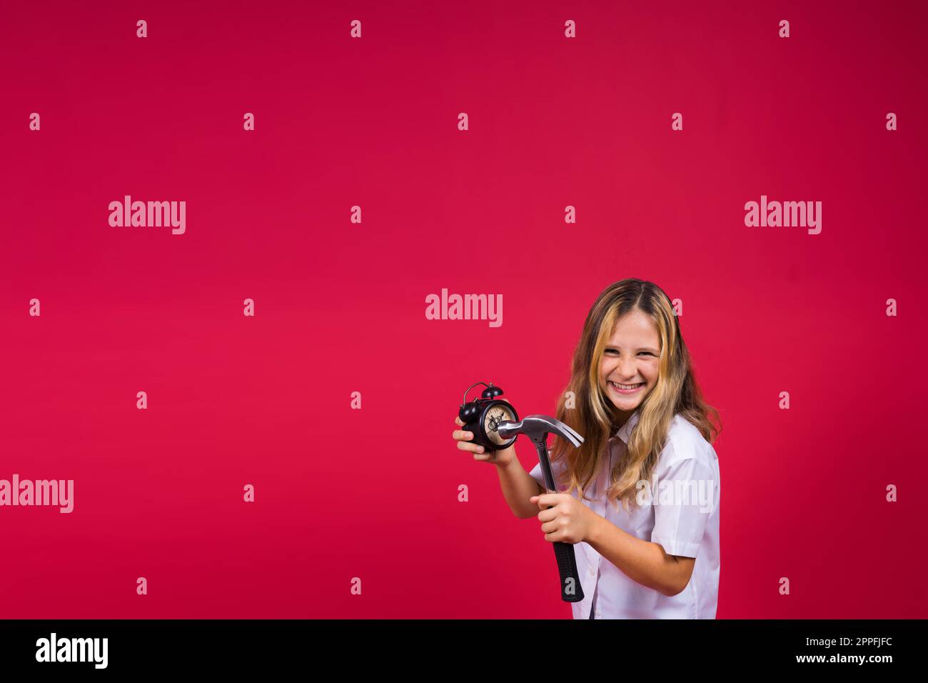 Petite fille tenant un marteau et un réveil souriant avec un sourire heureux et frais sur le visage. affichage des dents. Banque D'Images