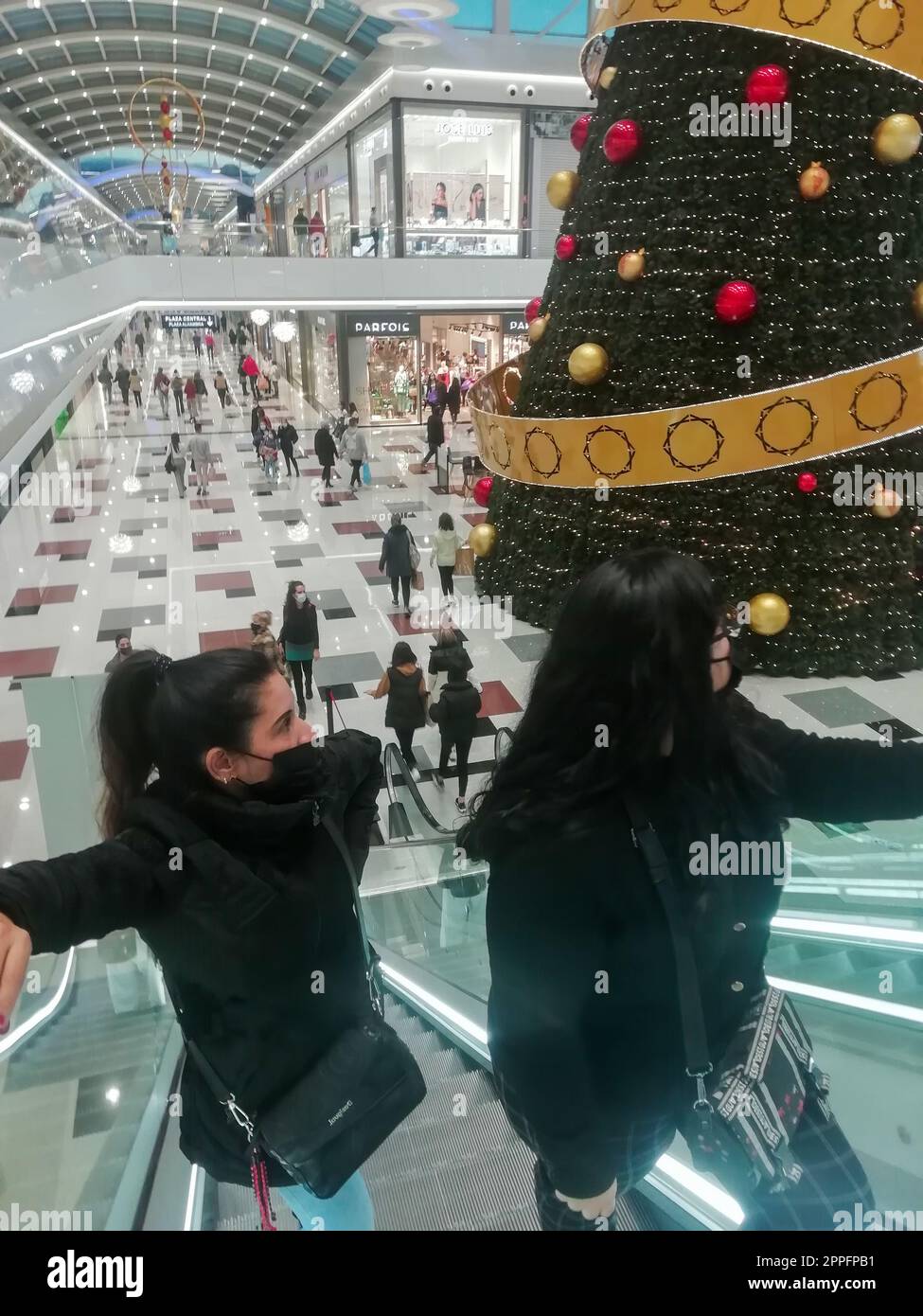 centre commercial sierra nevada, grenade espagne-décembre 22 2021 : deux femmes montent des escaliers mécaniques dans le centre commercial sierra nevada pendant les soldes d'hiver en regardant le grand sapin de noël. Banque D'Images