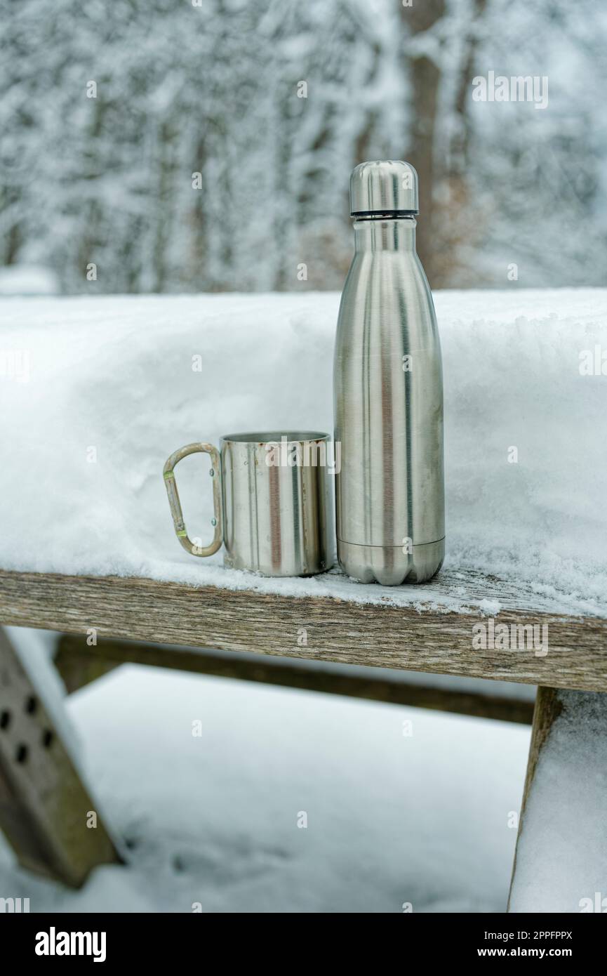 Thermos avec gobelet sur une table enneigée. Banque D'Images