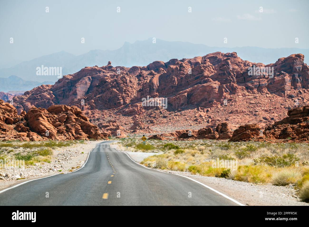 Route sinueuse dans le désert avec des montagnes rougeâtres dans le bkgrnd Banque D'Images
