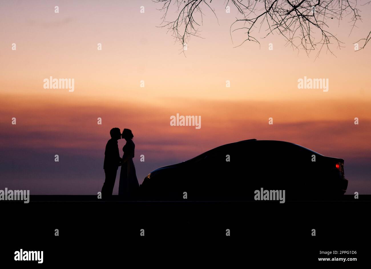 silhouette d'un couple de mariage amoureux au coucher du soleil près de la voiture. Banque D'Images