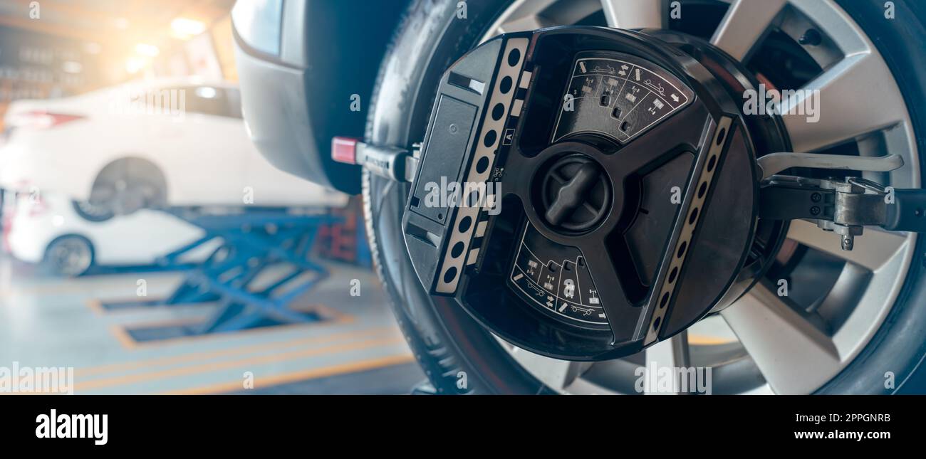 L'équipement de réglage de la géométrie des roues adhère au pneu de la roue de voiture dans l'atelier de réparation automobile. Alignement automatique des roues dans l'atelier de la station-service. Equilibre des roues de la voiture. Réglage de la suspension. Véhicule à l'intérieur de l'atelier de garage. Banque D'Images