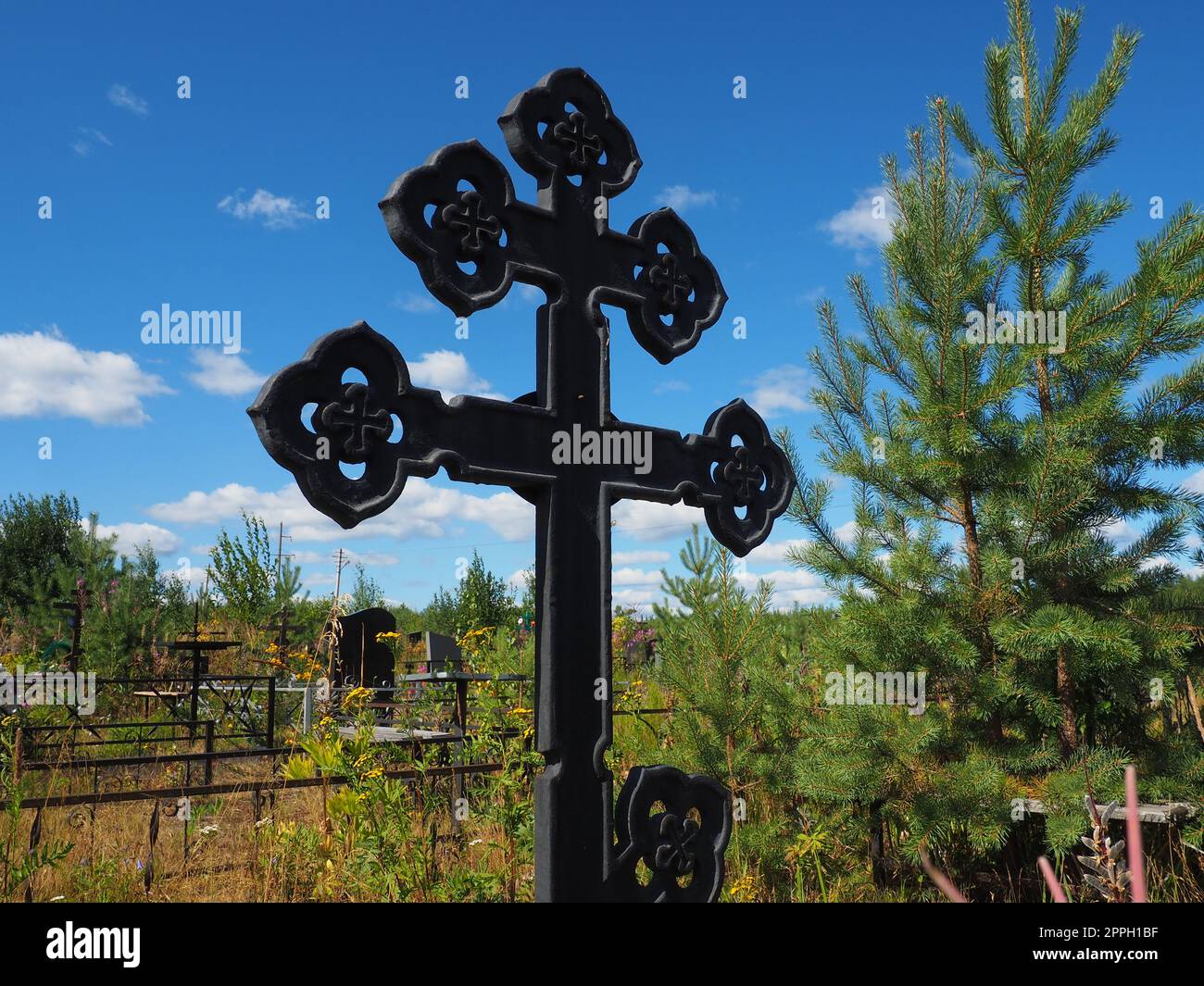Croix de métal sur la tombe. Monument en forme de croix dans le cimetière. Jour en été. Le thème du chagrin, de la mort et de l'Halloween. Symbole chrétien religieux du repos de l'âme Banque D'Images