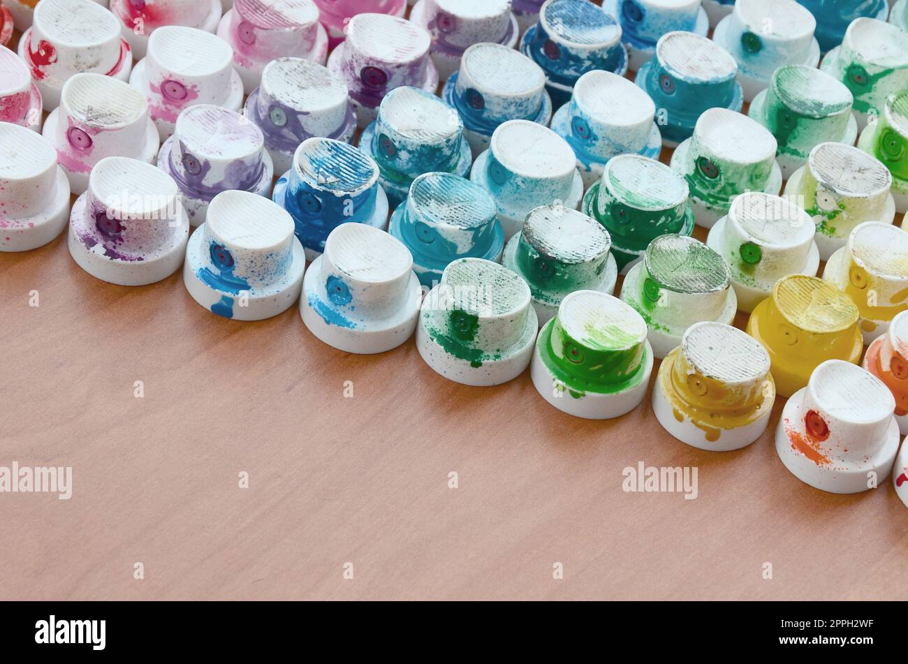 Un motif d'un grand nombre de buses d'un pulvérisateur de peinture pour dessiner des graffitis, tachés dans différentes couleurs. Les capuchons en plastique sont disposés en plusieurs rangées formant la couleur de l'arc-en-ciel Banque D'Images