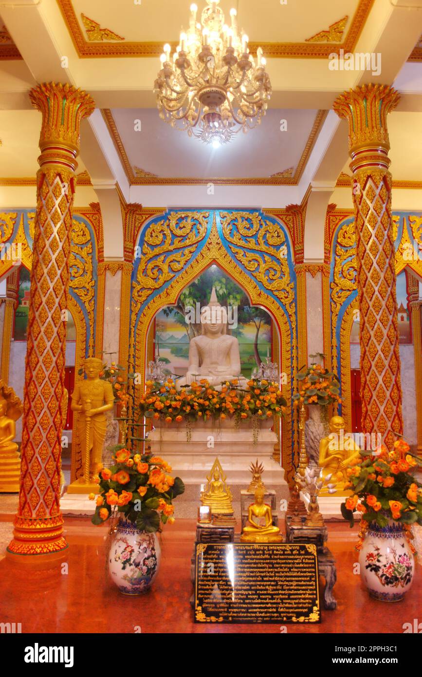 Statue en marbre d'un Bouddha assis dans une salle richement ornée au temple Wat Chalong, situé à Phuket, Thaïlande. Banque D'Images