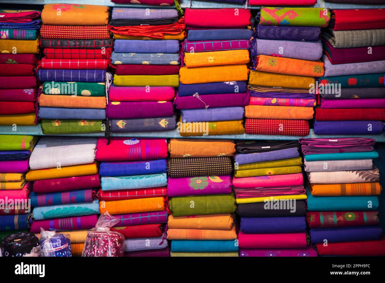 Variété artistique nuances de couleurs Saree's empilés sur le magasin de détail étagère à vendre Banque D'Images