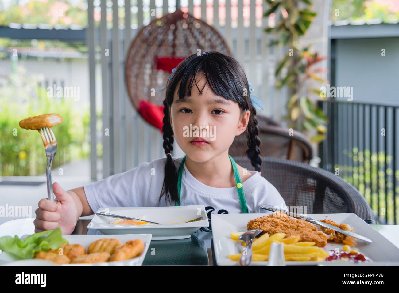 Jeune fille asiatique manger nuggets de poulet fast food sur table. Banque D'Images