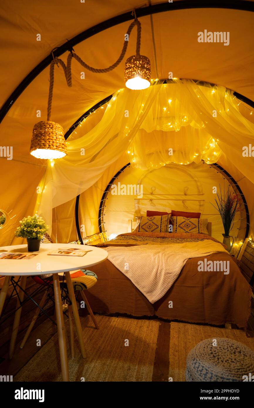 Tente avec lit très confortable, couvertures, oreillers et lumières, à un glamping Banque D'Images Tente avec lit très confortable, couvertures, oreillers et lumières, à un glamping Banque D'Images