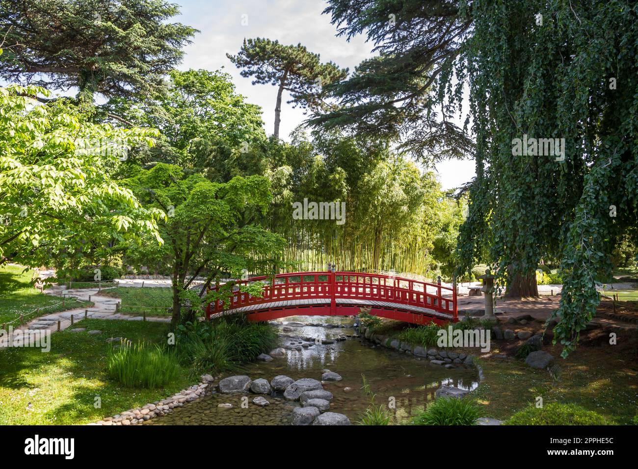 Pont traditionnel en bois rouge sur un étang de jardin japonais Banque D'Images