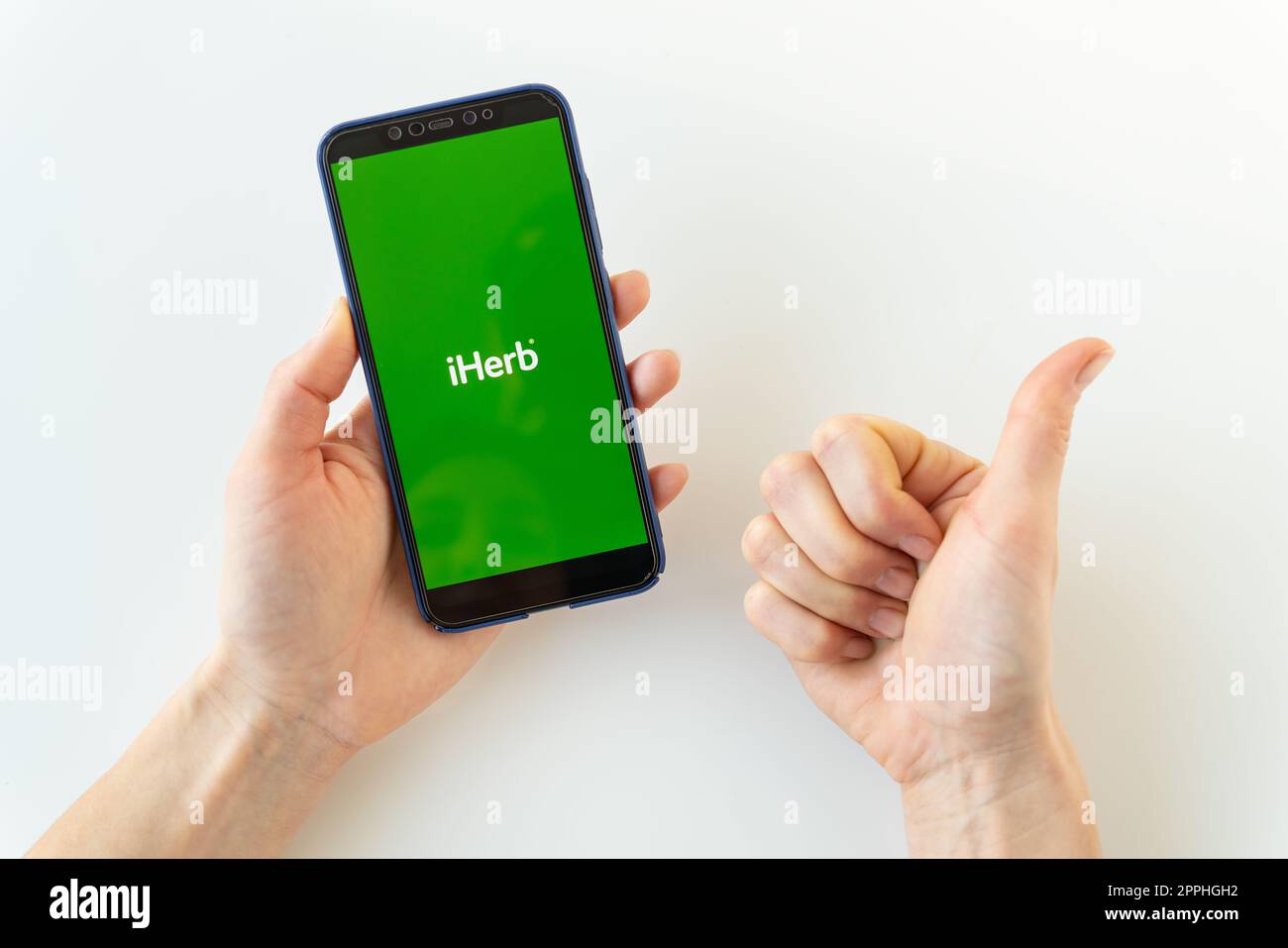 Kiev, Ukraine - 13 décembre 2022 : une femme tient un téléphone iPhone dans sa main avec une application de boutique en ligne iHerb avec un logo sur l'écran et montre comme au programme. Banque D'Images