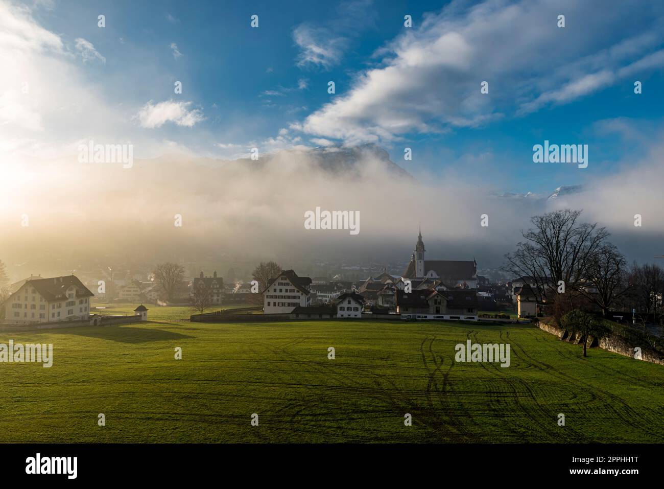 Brume matinale ou brume nocturne avec les rayons lumineux du soleil qui le pénètrent dans la ville de Schwyz en Suisse Banque D'Images