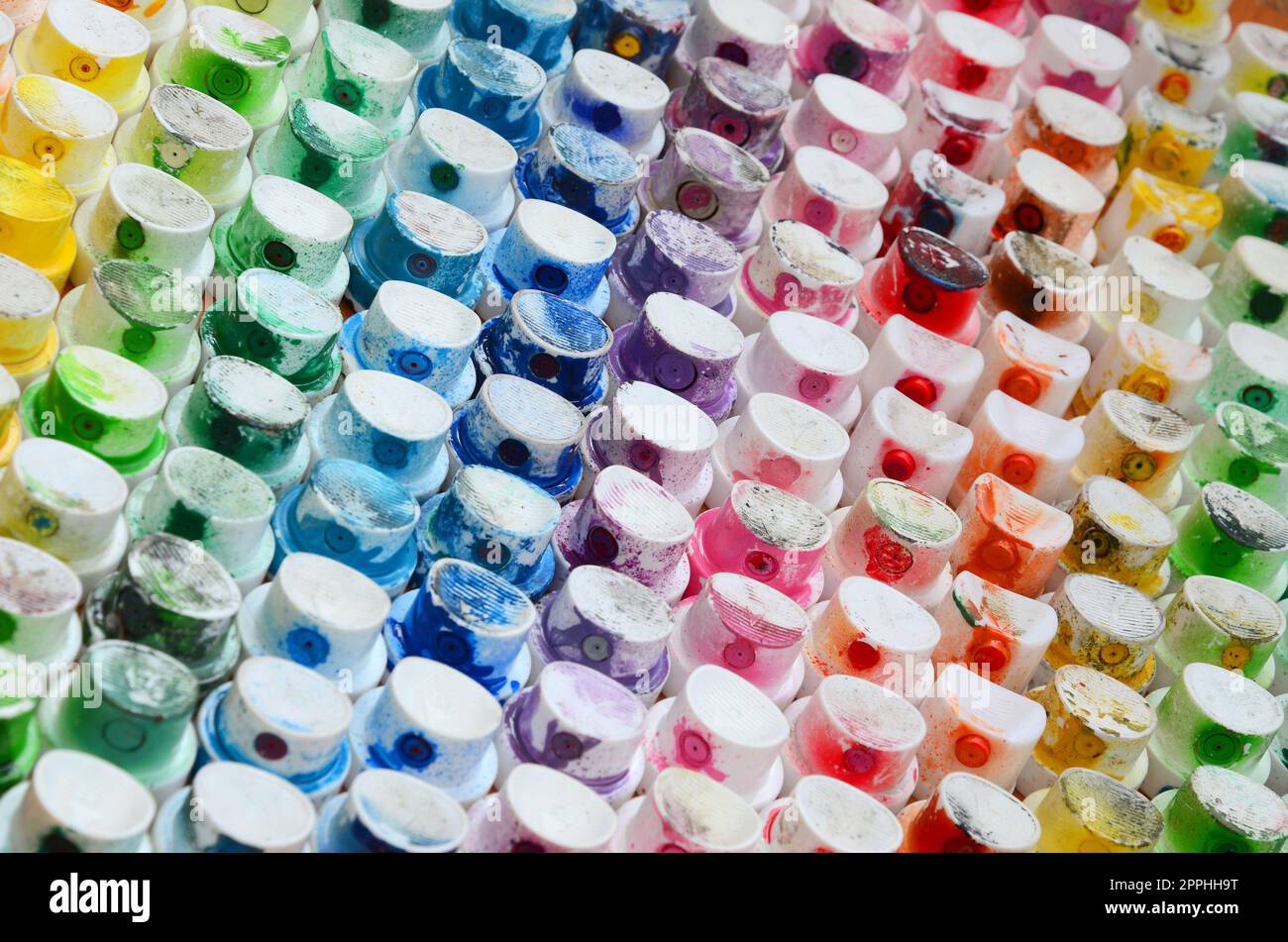Un motif d'un grand nombre de buses d'un pulvérisateur de peinture pour dessiner des graffitis, tachés dans différentes couleurs. Les capuchons en plastique sont disposés en plusieurs rangées formant la couleur de l'arc-en-ciel Banque D'Images