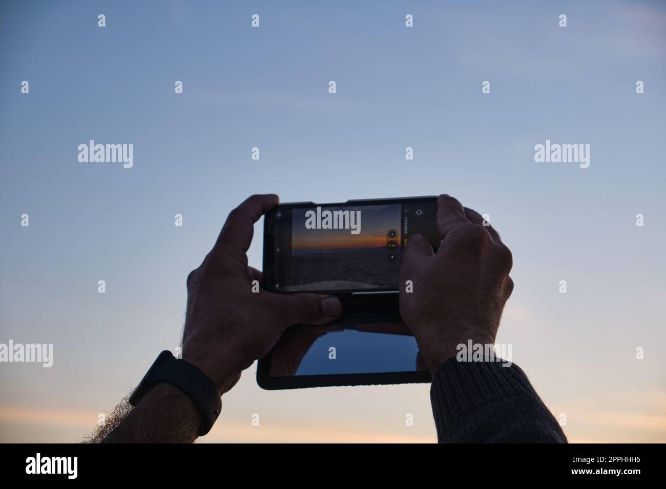Touriste essayant de capturer le soleil couchant sur Athènes sur son téléphone portable au printemps Banque D'Images