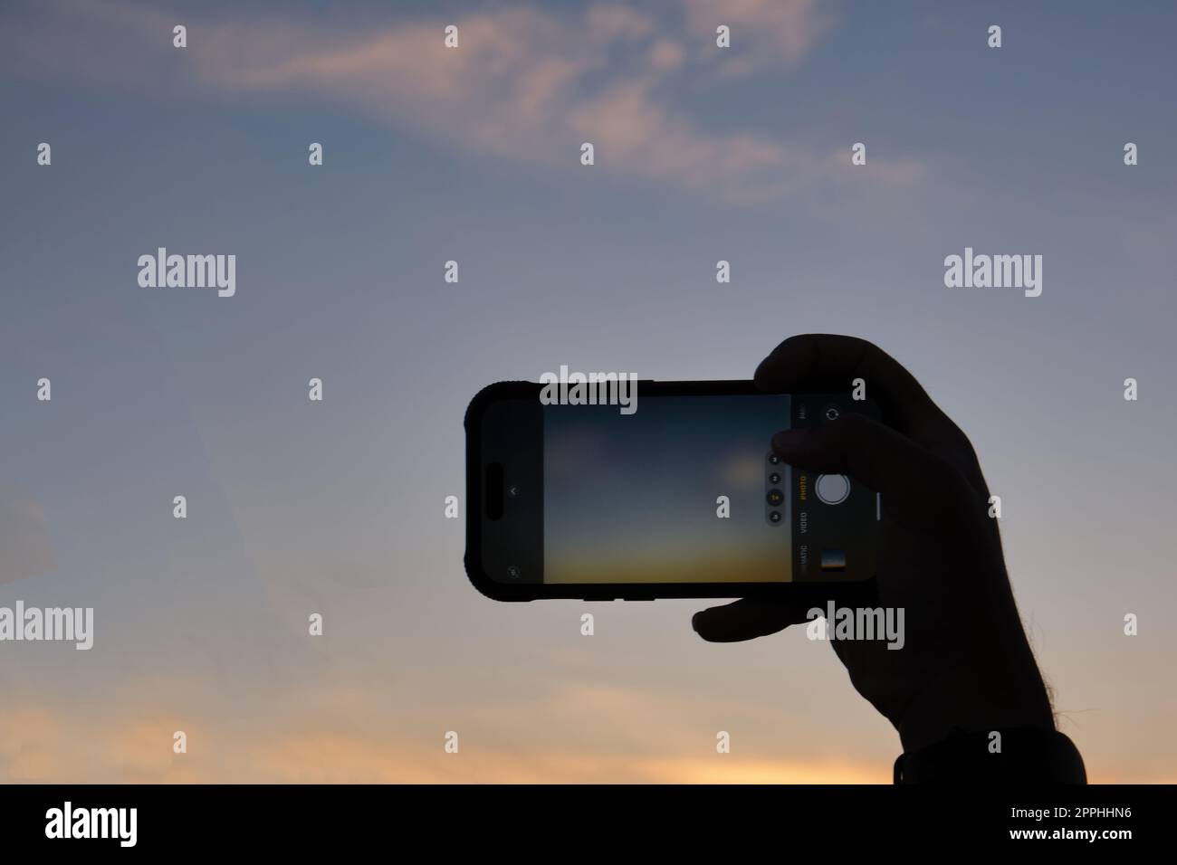 Touriste essayant de capturer le soleil couchant sur Athènes sur son téléphone portable au printemps Banque D'Images