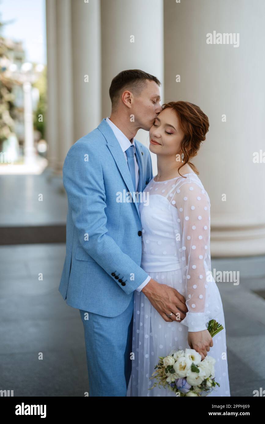 mariée dans une robe de mariée légère au marié dans un costume bleu Banque D'Images