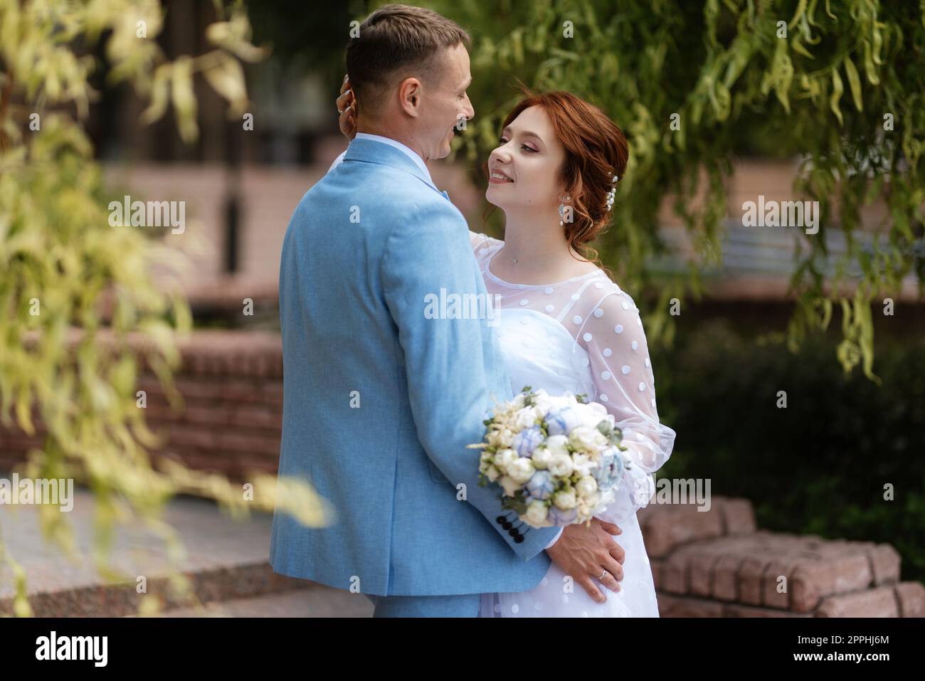 mariée dans une robe de mariée légère au marié dans un costume bleu Banque D'Images