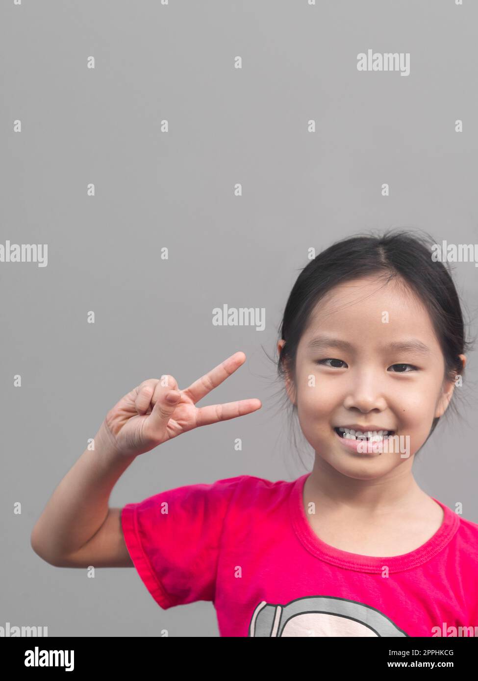 Petite fille asiatique mignon sourire avec sa dent cassée, fond gris Banque D'Images